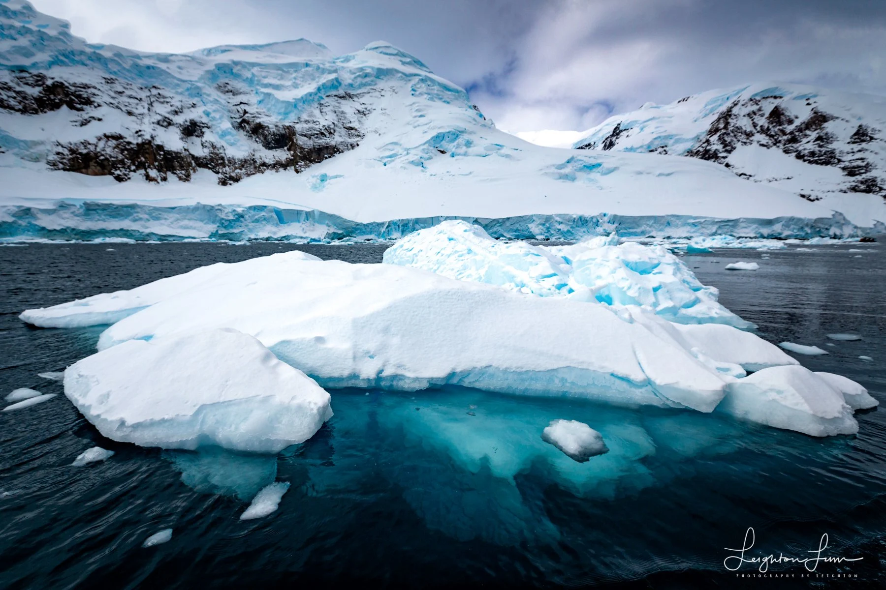 A blue iceberg in front of snow-covered mountains — Antarctica photography expedition
