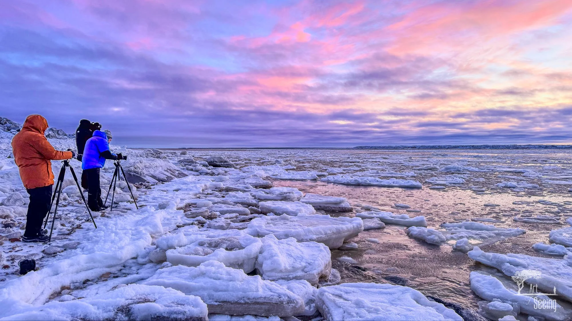 Photographers with tripods on the frozen shore of Hudson Bay at sunset
