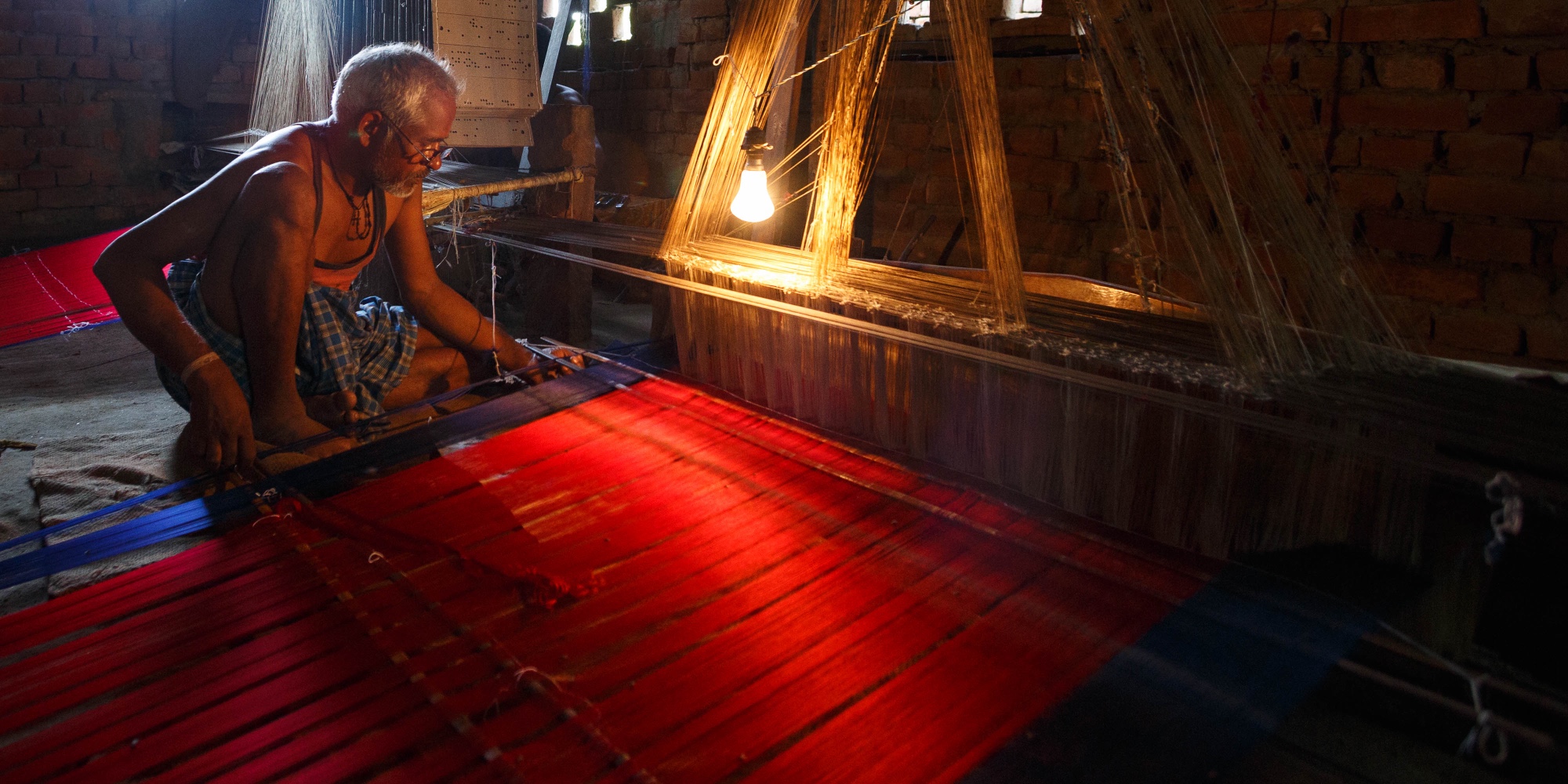 A weaver at his loom, silk catching the light