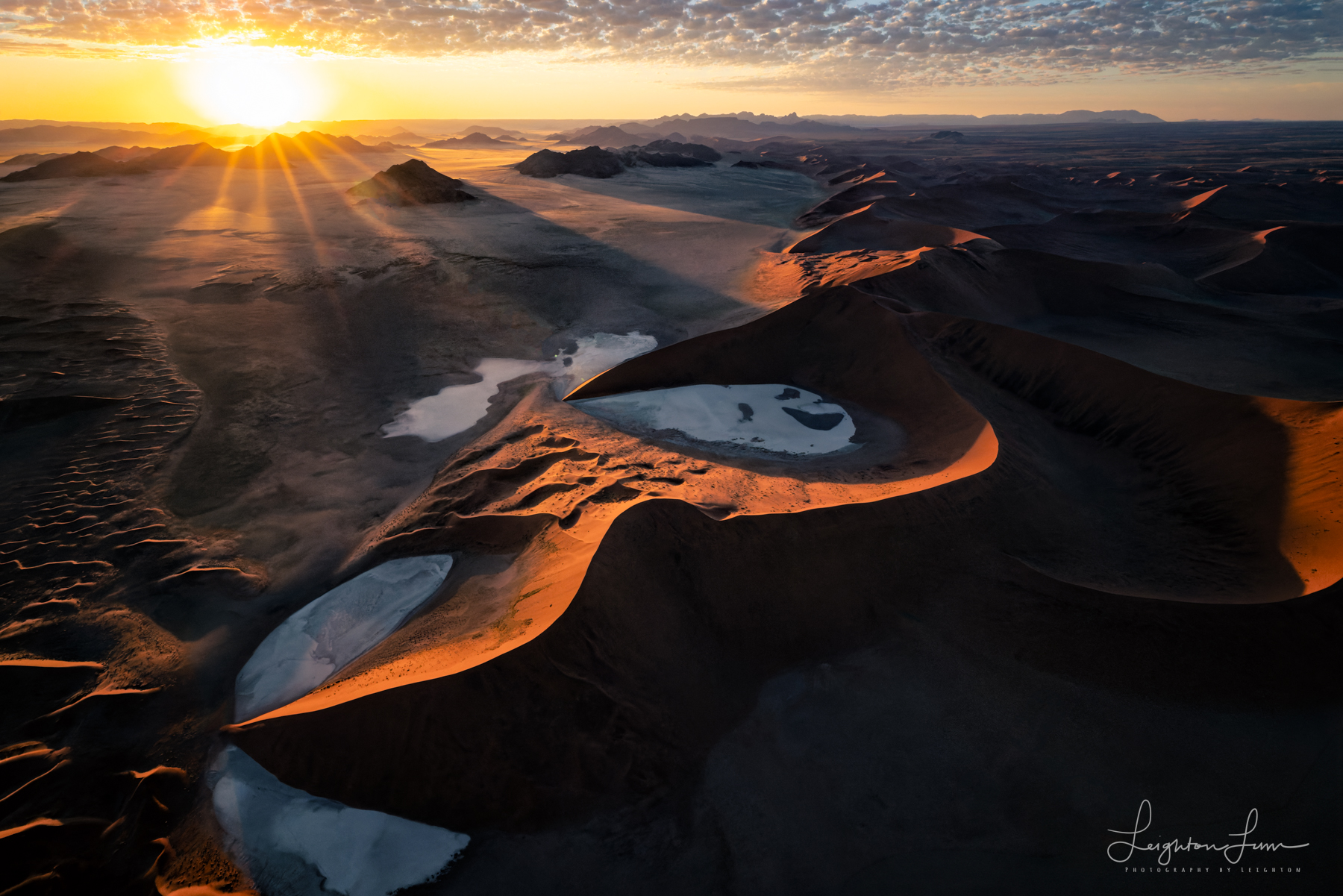 Sun rising over Namib desert dunes and salt pans from the air, Namibia