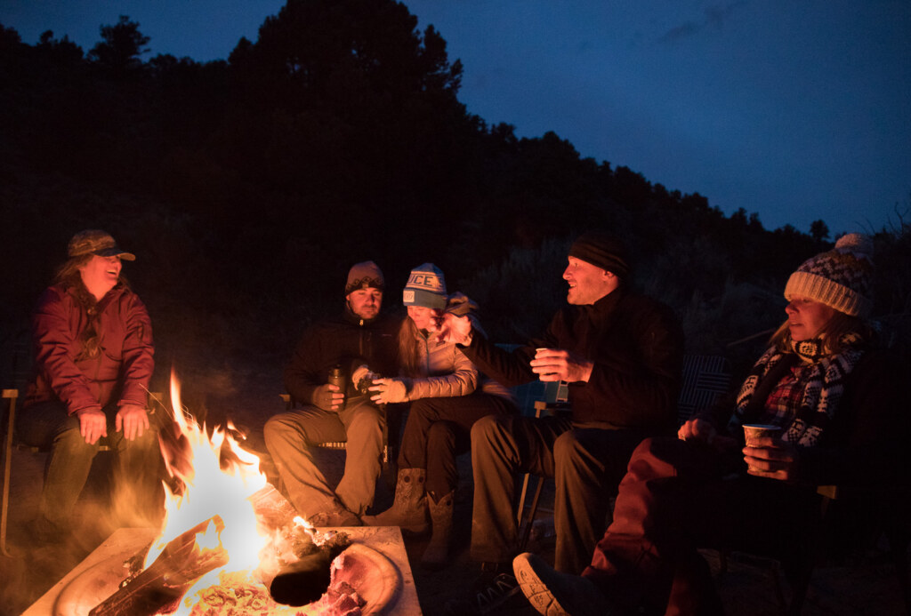 Workshop participants around a campfire at dusk