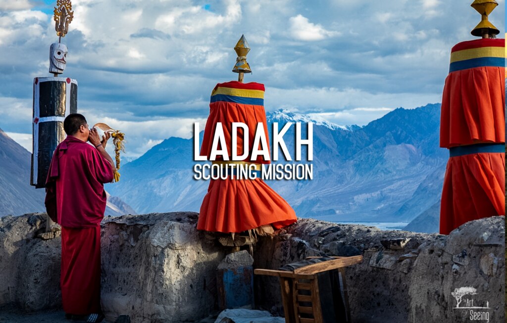 A monk in red robes on a monastery roof, Himalayan peaks beyond