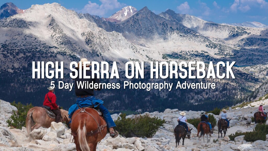 Riders on horseback crossing a High Sierra basin below snow-covered peaks